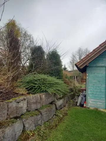 Gartenpflege entlang der Natursteinmauer